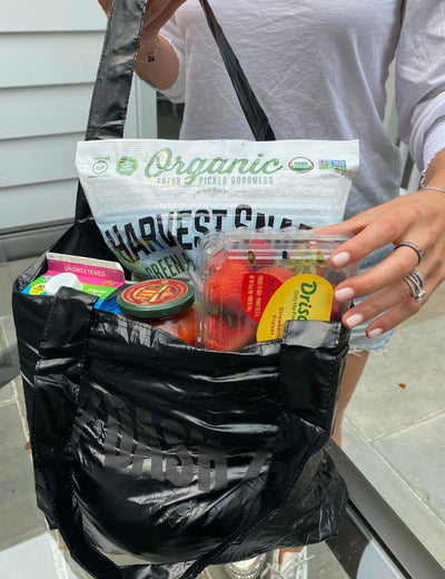 Reusable shopper tote filled with strawberries, tomato sauce, chips, almond milk