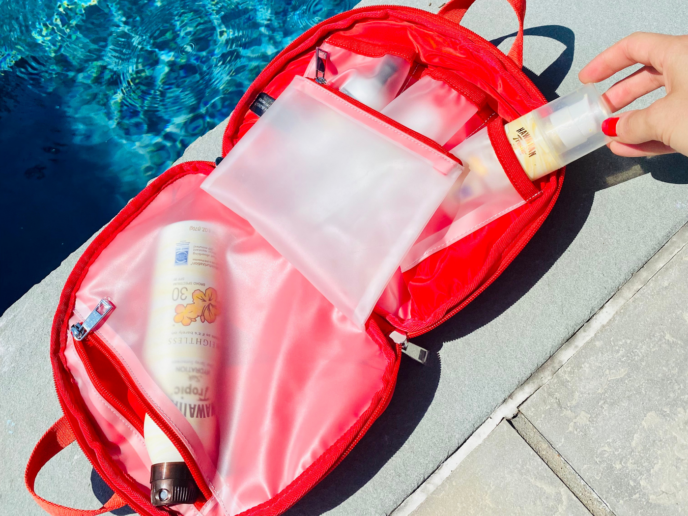 Red toiletry case packed up with SPF for a day at the pool #color_cherry-red